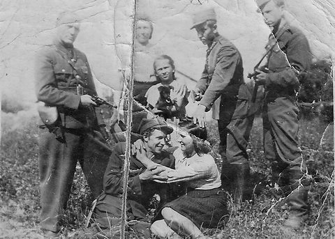 Grupa umundurowanych mężczyzn, kobiet i dziewczynki na fotografii opisanej jako Partyzantka w okolicach Draganowej